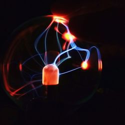 Close-up of illuminated candles over black background