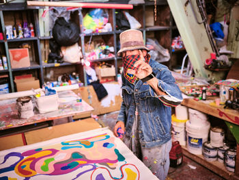 An artist with face covering works in their art studio.