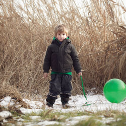 Portrait of boy with helium balloon standing on snow