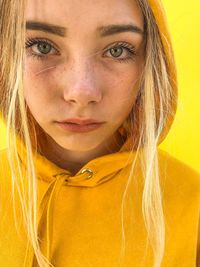 Close-up of teenage girl with blond hair against yellow background