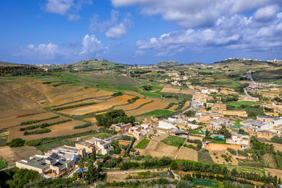 Aerial view of agricultural field by houses against sky