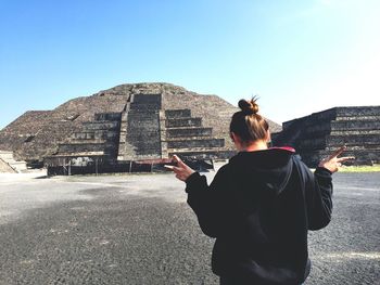 Young woman standing against clear sky