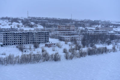 Buildings on snow covered land against sky