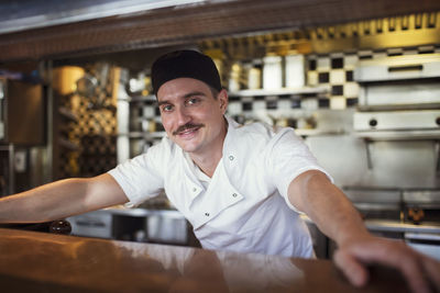 Portrait of happy waiter standing at restaurant