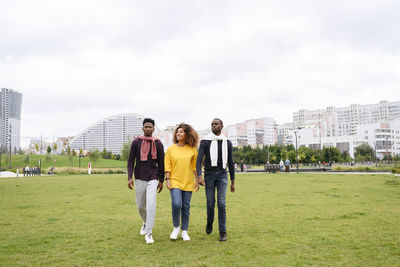 Friends walking on grass in park