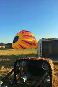 Hot air balloon on field against clear sky