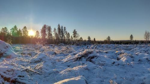 Snow covered landscape against clear sky during winter