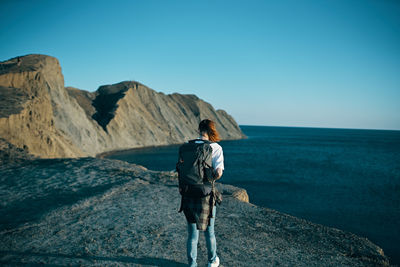 Rear view of man looking at sea against clear sky