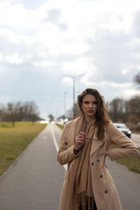 Young woman standing on road against sky