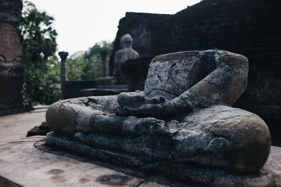 Damaged statue at temple against clear sky