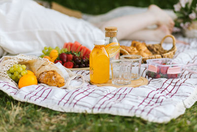 Fresh fruits and drinks on a picnic blanket.