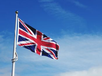 Low angle view of flag against blue sky