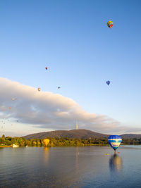 Hot air balloons flying over water against sky