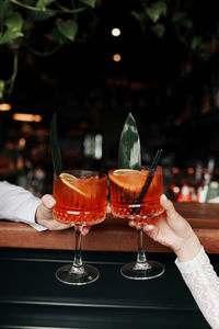 Midsection of woman holding wineglass on table