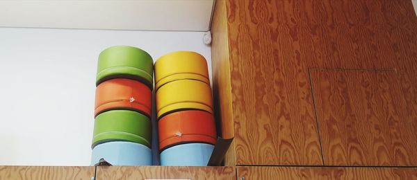 Low angle view of multi colored pencils on table against wall