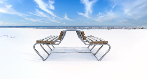 Empty chair on snow covered winter  beach against sky in jurmala 