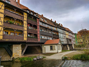 Buildings by river against sky