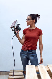 Young woman photographing against wall