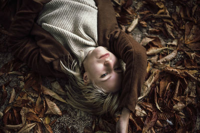 Portrait of a blonde woman lying in the autumn leaves.