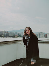 Portrait of young woman standing against sky