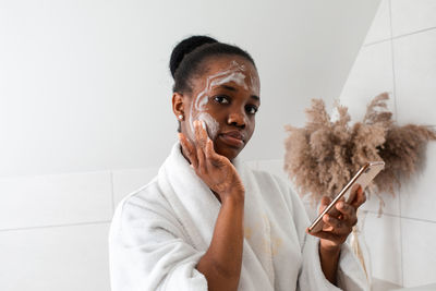 Portrait of young woman applying make up on face