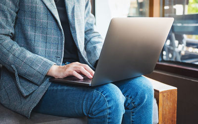 Midsection of woman using laptop at home