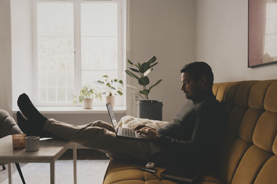 Businessman using laptop while sitting on sofa at office