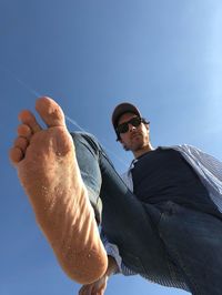 Low angle view of man with barefoot against sky