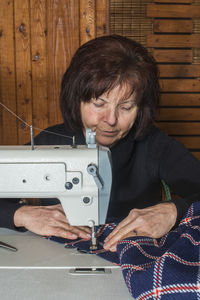 Senior woman sewing textile on machine