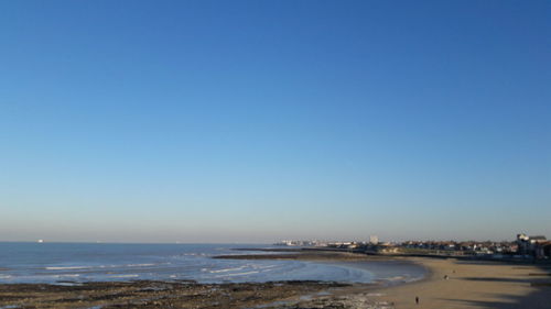 Scenic view of beach against clear blue sky