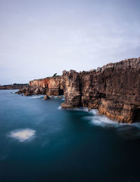 Scenic view of sea and cliff against sky