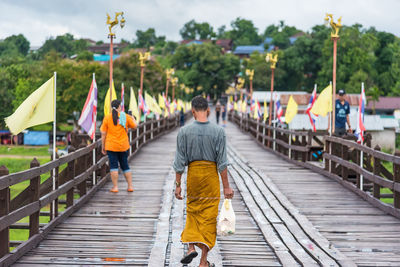 Rear view of people walking on footbridge