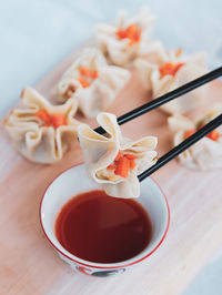 Close-up of chinese dimsum on wood chopper board with hot sauce