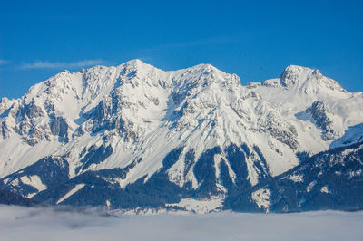 Scenic view of snowcapped mountains against blue sky