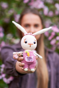 Knitted toy hare in the hands of a young girl.
