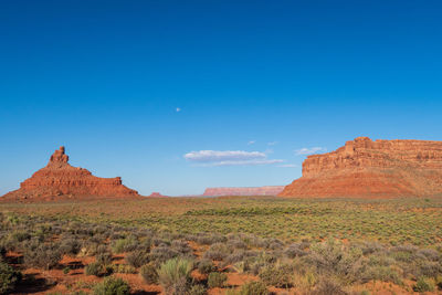 Landscape of orange and red buttes and monoliths amidst desert at valley of the gods in utah