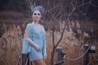 Portrait of young woman standing against bare tree