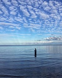 Man fishing in sea against sky