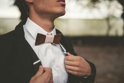 Midsection of man wearing suit and bow tie outdoors