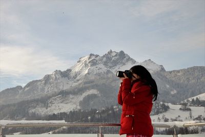 Woman photographing against snowcapped mountain 