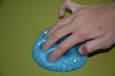 Cropped hand touching blue slimy toy on table