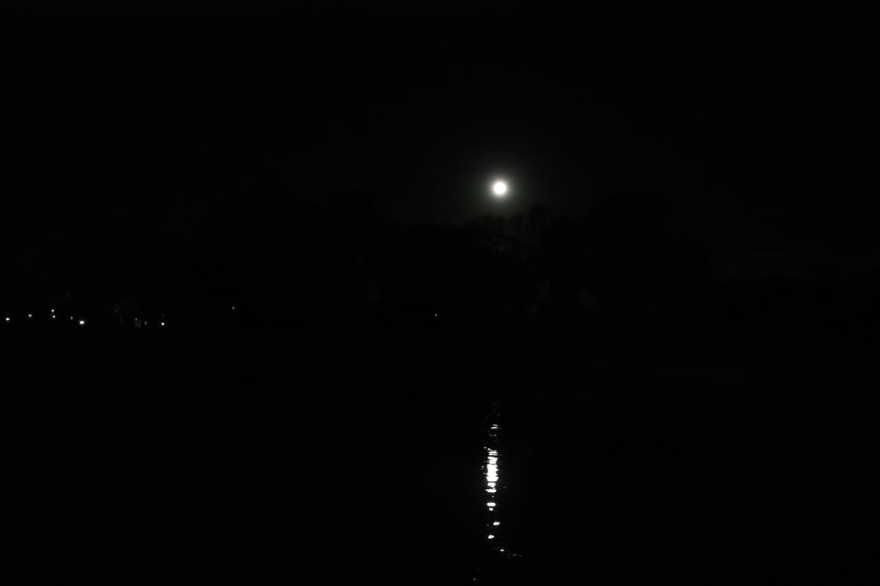 REFLECTION OF ILLUMINATED LIGHTS IN LAKE AGAINST SKY