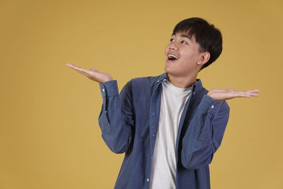 Man looking away while standing against yellow background