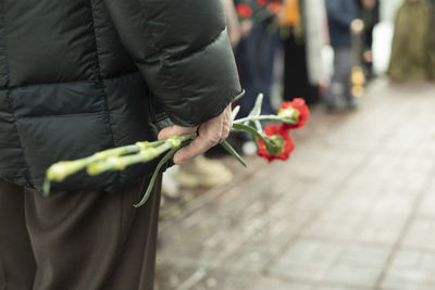 Two carnations in man's hand. details of funeral ceremony. commemorative flowers in hand. 