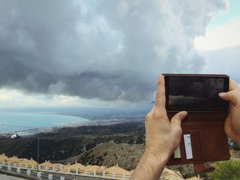 Cropped image of person against cloudy sky