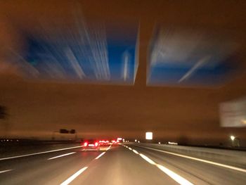 Light trails on highway against sky at night