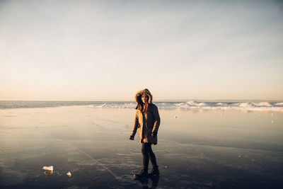 Woman standing in sea against sky