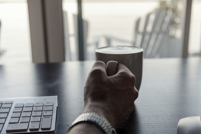 Cropped hand having drink at desk