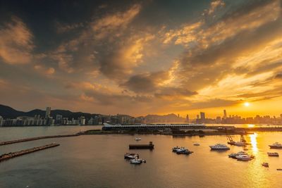 Boats moored at harbor against sky during sunset