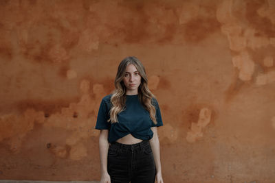 Portrait of young woman standing against wall